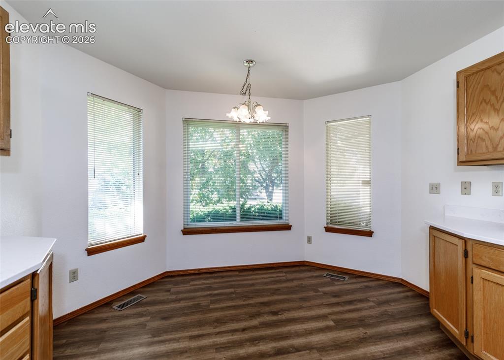 Image 6 of 22: Bay window with three windows, wood-finish flooring, overhead chandelier, l
