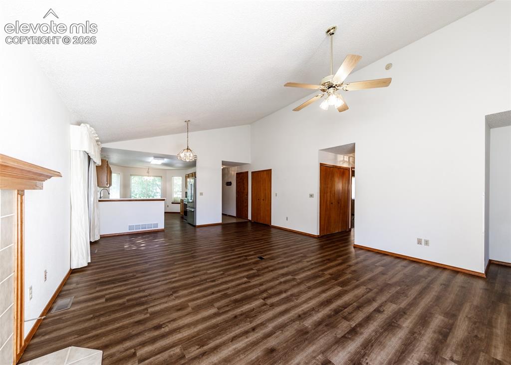 Image 7 of 22: Vaulted ceiling, wood-finish flooring, ceiling fan, fireplace with wood man