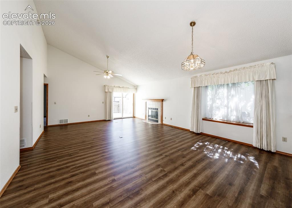 Image 8 of 22: Wood-finish flooring, vaulted ceiling, built-in fireplace, ceiling fan, and