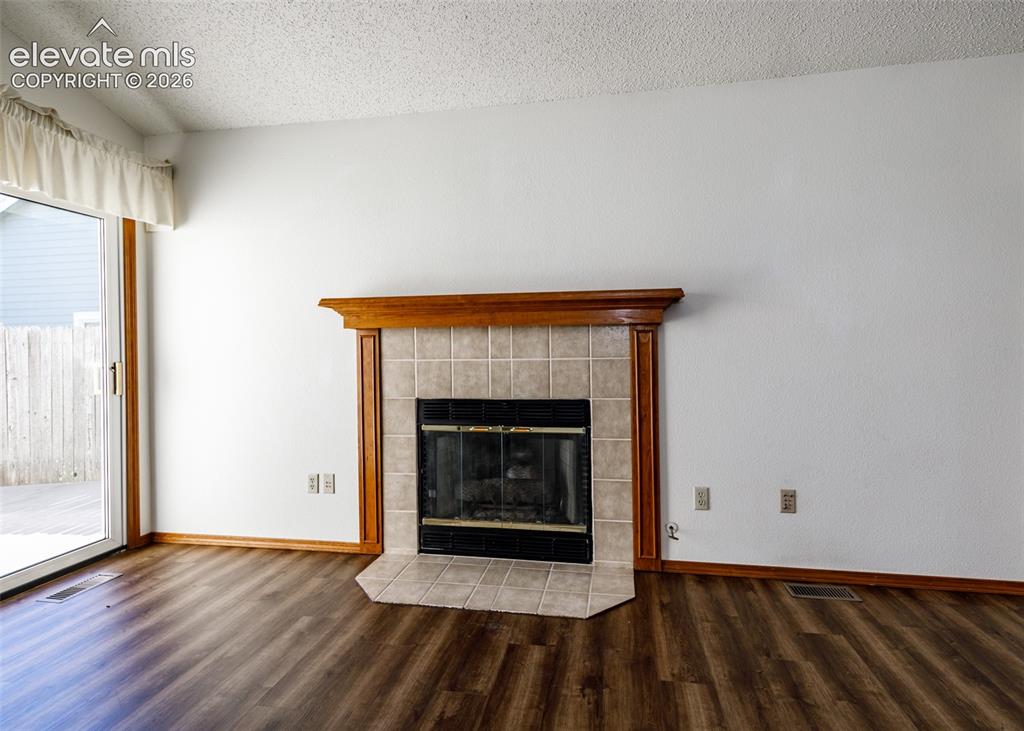 Image 9 of 22: Wood-finish flooring, fireplace with tile surround, wood mantel, and glass 