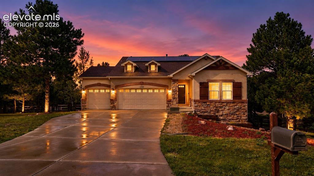Caption: Stucco exterior with stone accents, dormer windows, and a multi-car garage