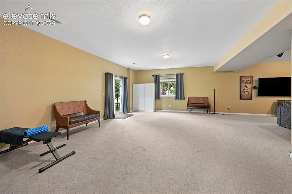 Image 12 of 43: Spacious room with light-colored carpeting, recessed lighting, and a neutra