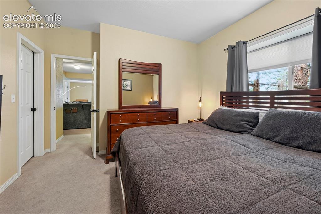 Image 17 of 43: Carpeted flooring, a window with shades, a wooden headboard, and a wooden d