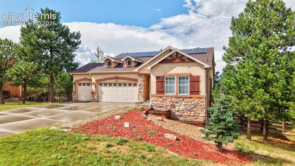 Image 2 of 43: Exterior with stucco siding, stone accents, solar panels, and a two-car gar