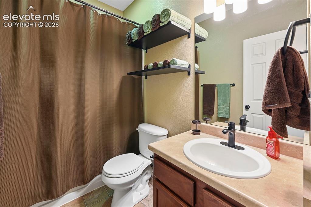 Image 27 of 43: Vanity with a single oval sink, dark wood-finish cabinetry, and solid surfa