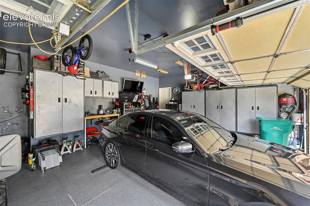 Image 30 of 43: Garage featuring integrated overhead storage, multiple built-in metal stora
