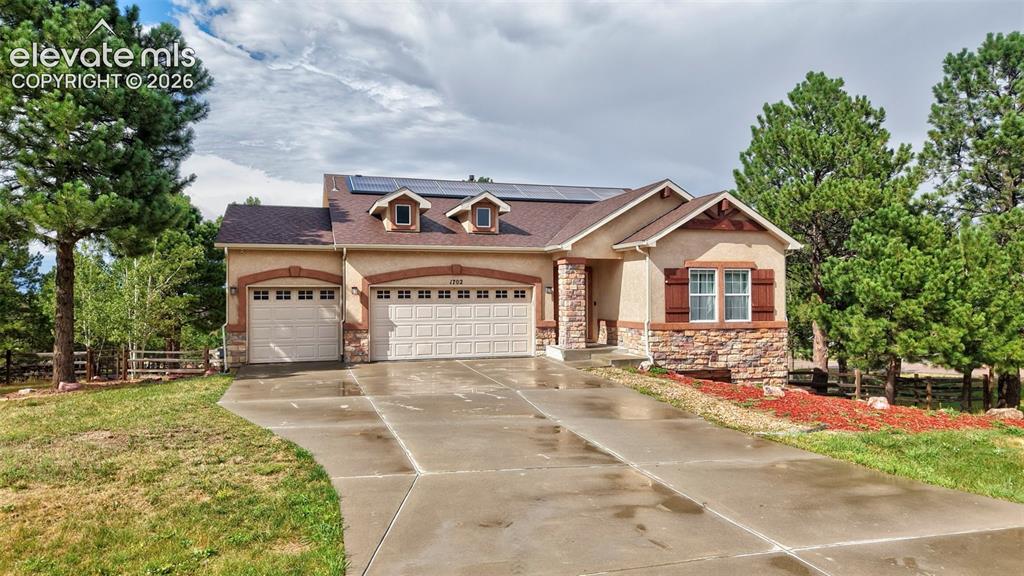Image 32 of 43: Stucco exterior featuring stone accents, a multi-car driveway, and mature t