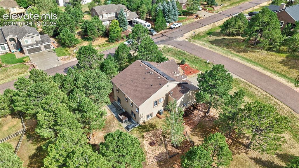 Image 39 of 43: Two-story residence with a brown shingle roof, solar panels, and a surround