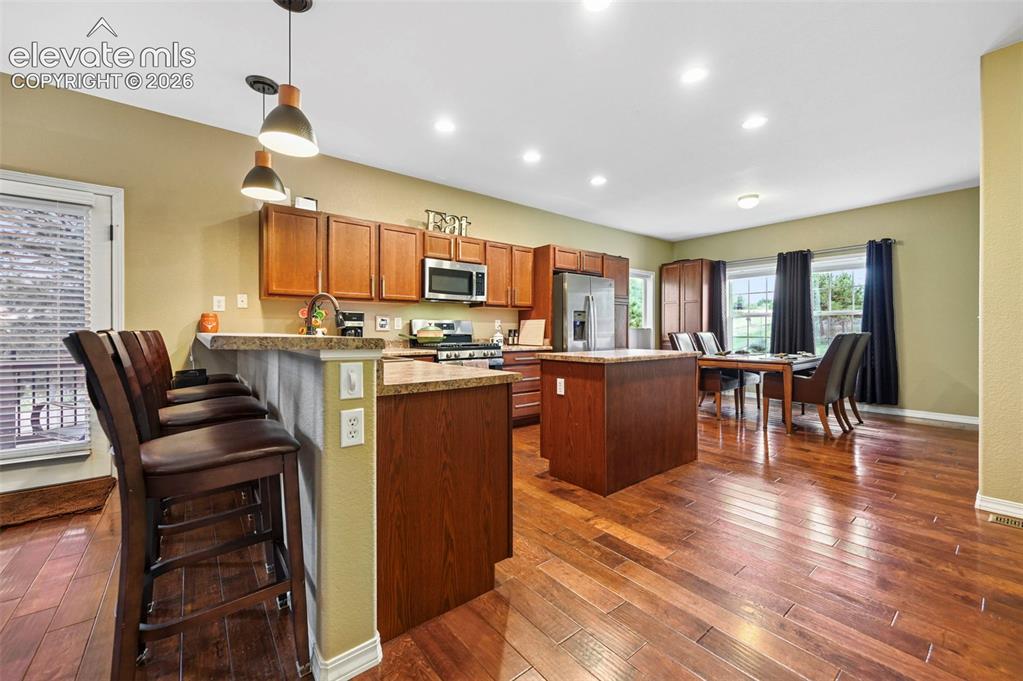 Image 5 of 43: Open-concept kitchen and dining area featuring wood-finish flooring, wood c