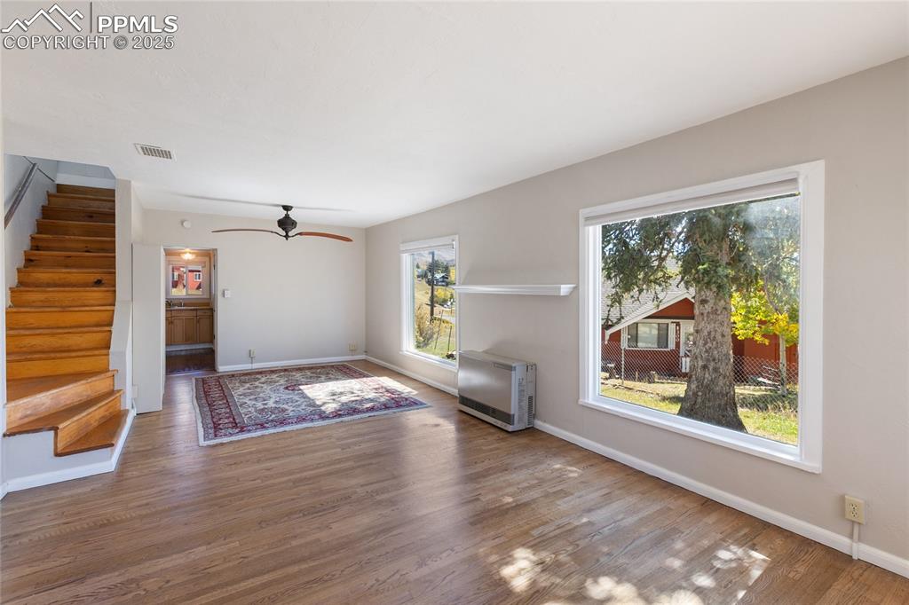 Image 13 of 49: Unfurnished living room with stairway, heating unit, wood finished floors,