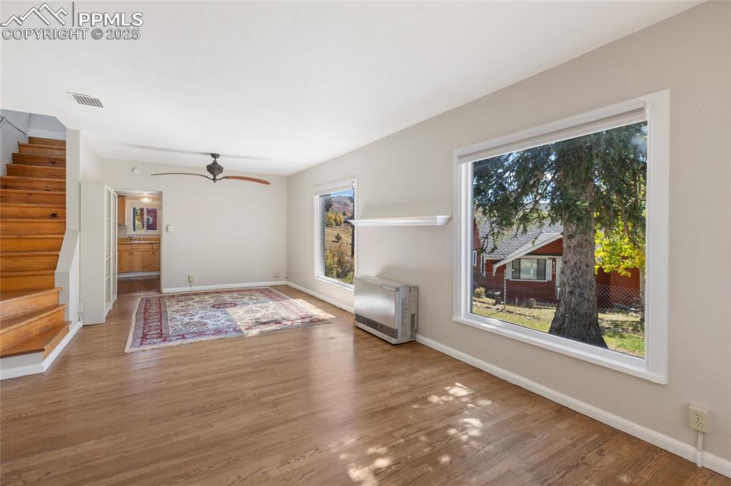 Image 15 of 49: Unfurnished living room with stairway, wood finished floors, heating unit,