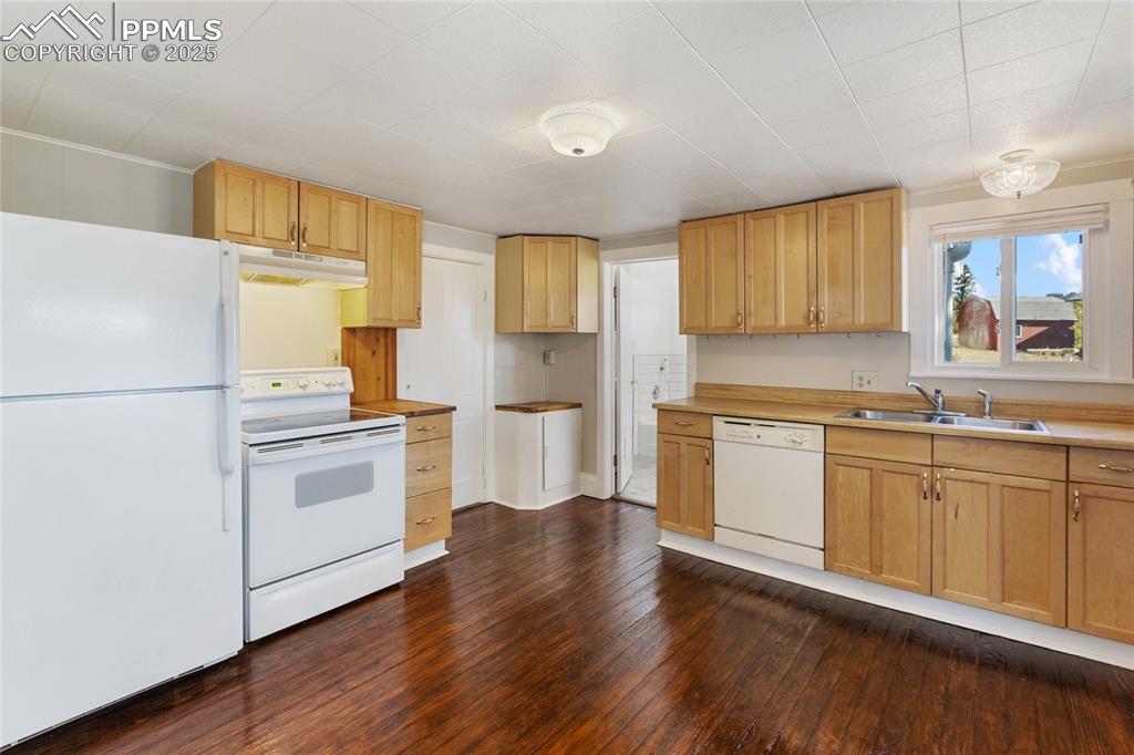 Image 16 of 49: Kitchen featuring white appliances, dark wood-style flooring, light counter
