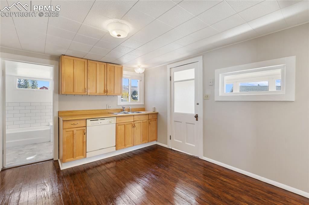 Image 17 of 49: Kitchen with light countertops, light brown cabinets, dishwasher, and dark