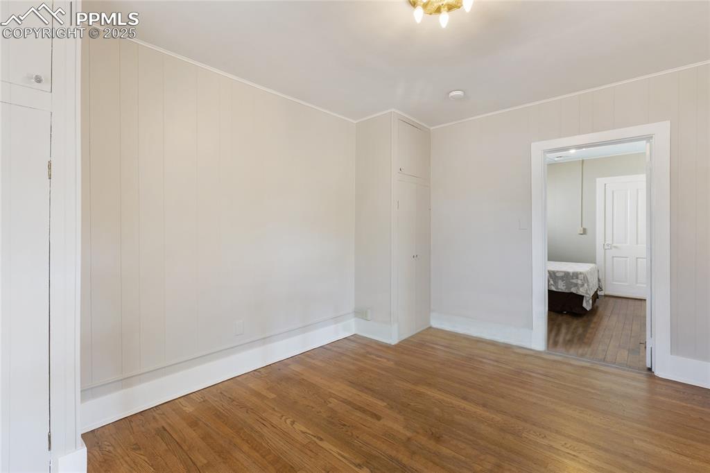 Image 27 of 49: Spare room featuring hardwood / wood-style flooring, ornamental molding, an