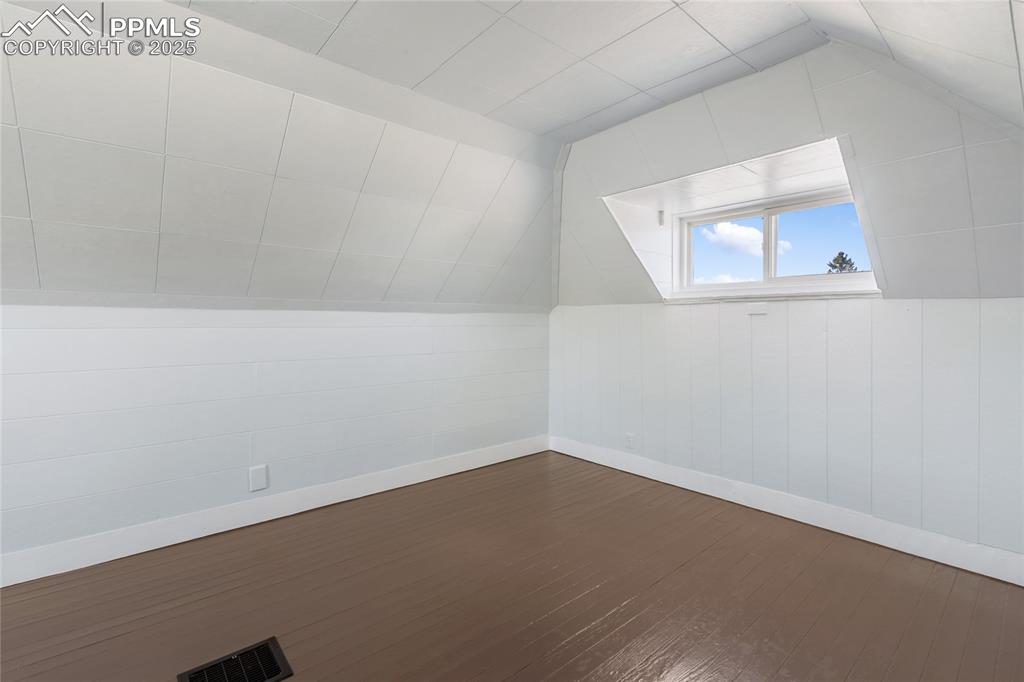 Image 33 of 49: Additional living space with lofted ceiling and dark wood-style floors