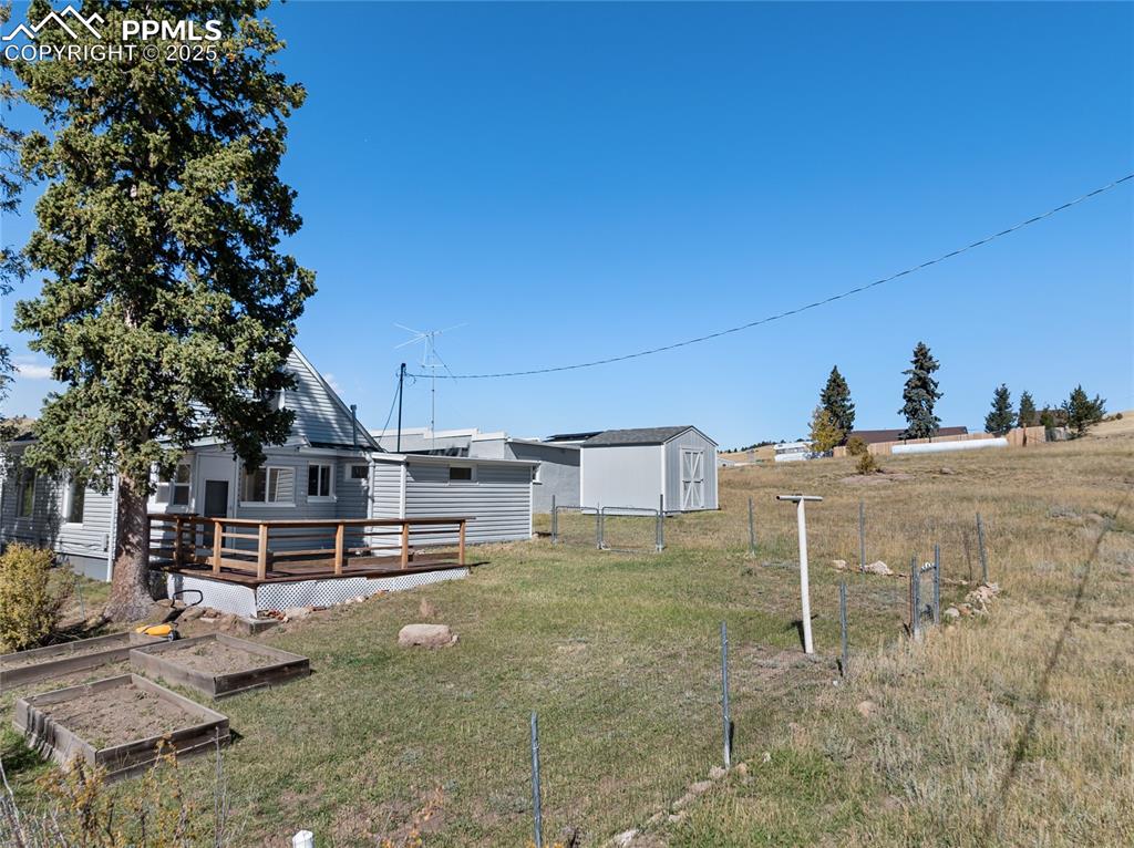 Image 39 of 49: View of yard featuring a wooden deck, a vegetable garden, and a shed