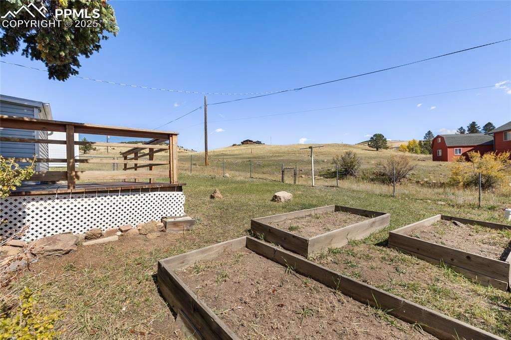 Image 42 of 49: View of yard featuring a view of rural / pastoral area, a deck, and a veget