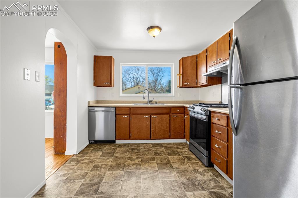 Image 10 of 25: Kitchen featuring a sink, brown cabinets, stainless steel appliances, light