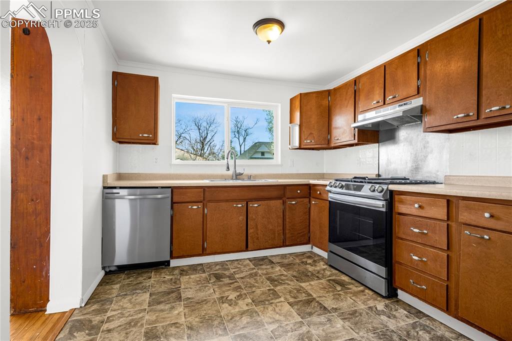 Image 11 of 25: Kitchen featuring a sink, brown cabinets, stainless steel appliances, light