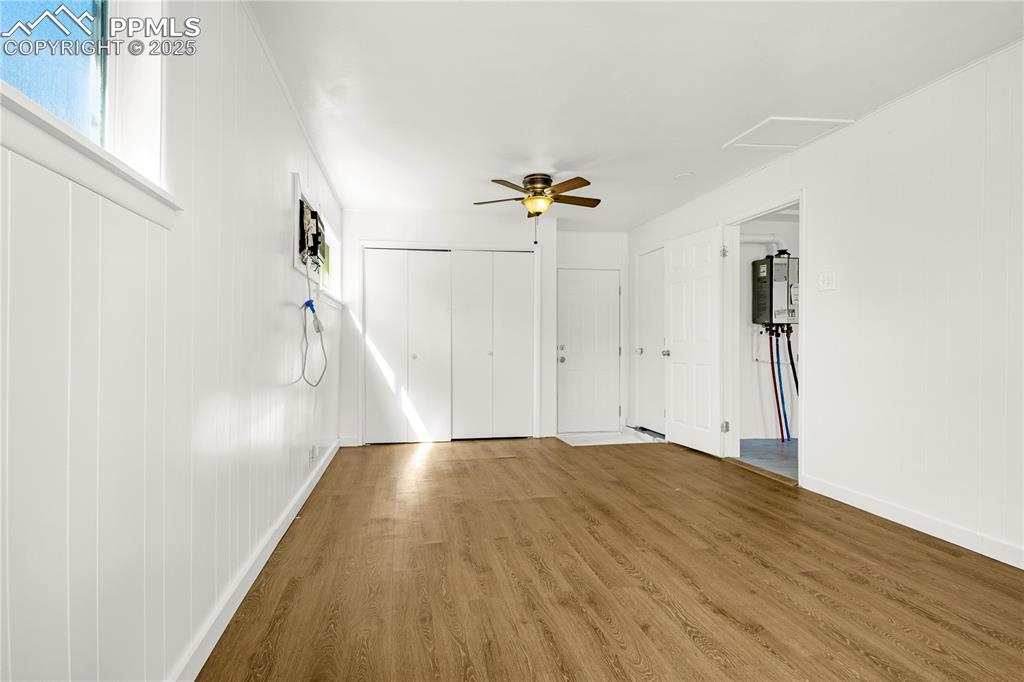 Image 13 of 25: Unfurnished living room featuring water heater, wood finished floors, baseb