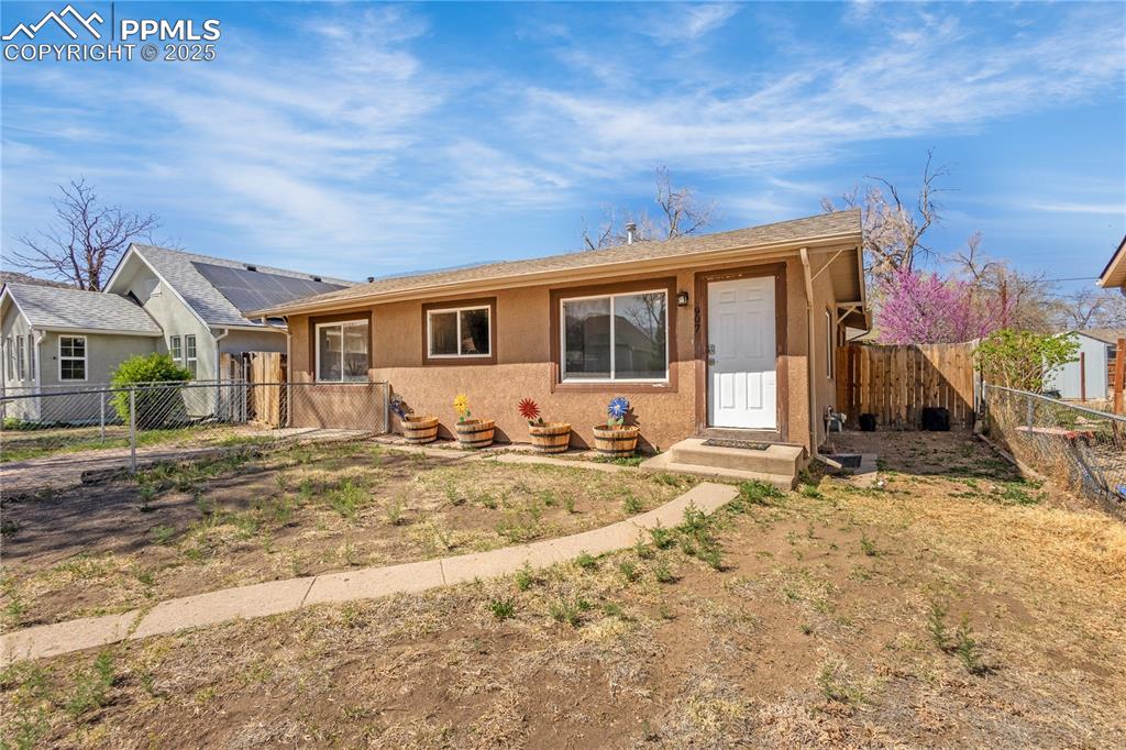 Image 2 of 25: View of front of home with a fenced backyard and stucco siding
