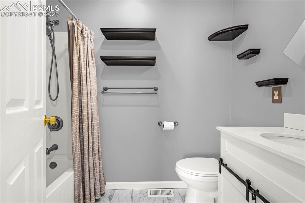 Image 7 of 25: Full bathroom with vanity, toilet, baseboards, marble finish floor, and sho