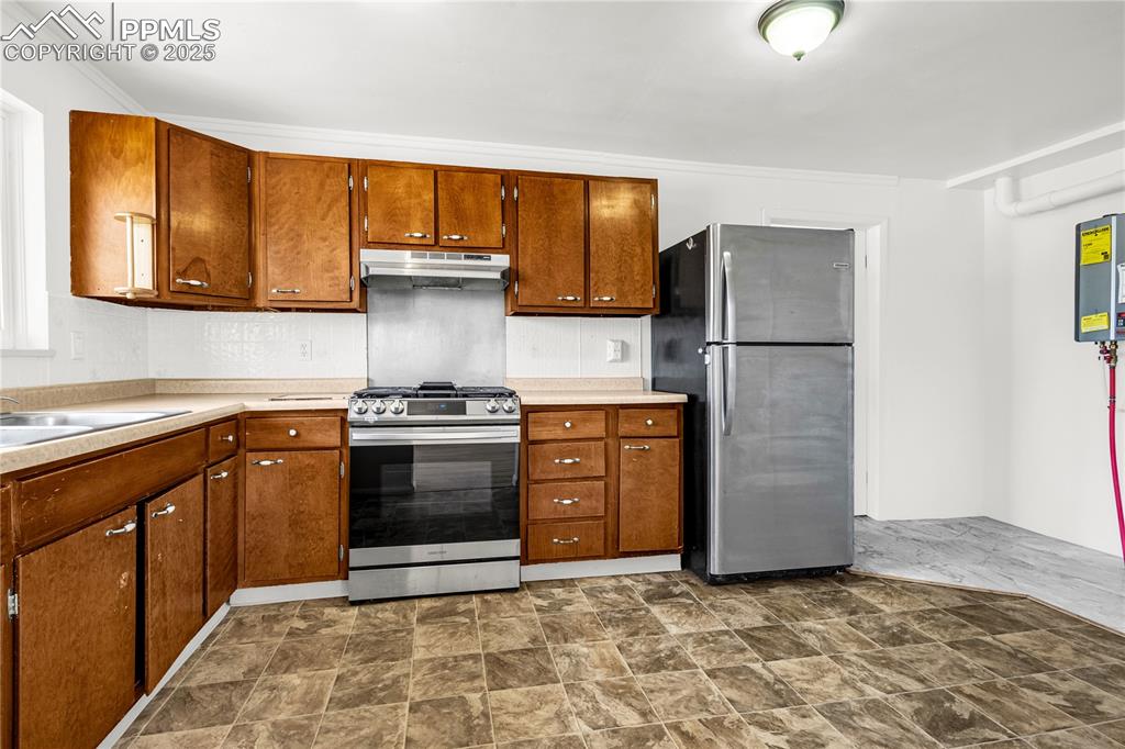 Image 9 of 25: Kitchen with under cabinet range hood, stainless steel appliances, light co