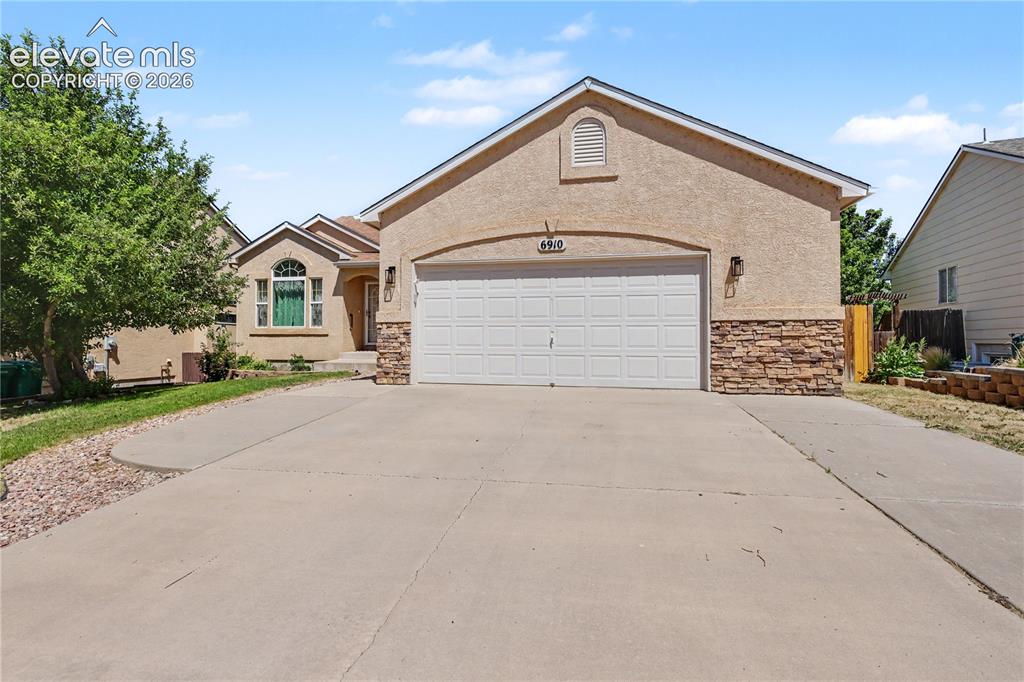 Image 1 of 41: Stucco exterior with a stone veneer accent, attached garage, and a concrete
