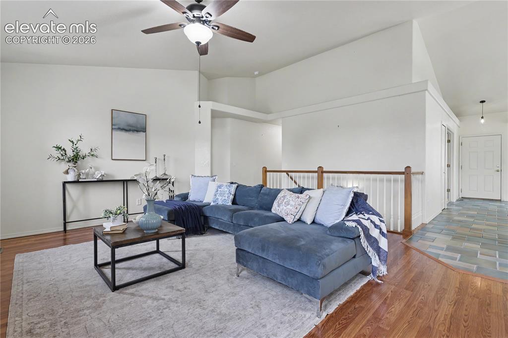 Image 10 of 41: Vaulted ceiling living space featuring wood-finish flooring and a ceiling f
