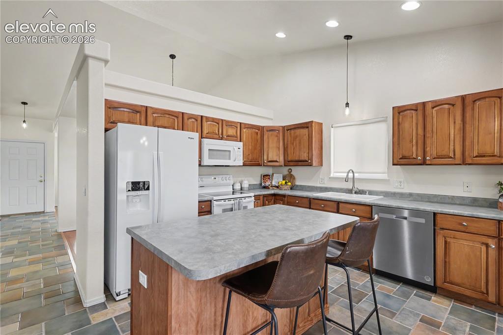 Image 14 of 41: Expansive kitchen featuring a central island with seating, wood cabinetry,