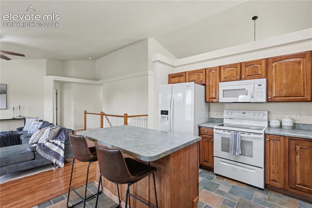 Image 15 of 41: Kitchen featuring wood cabinetry, white appliances, a peninsula island with