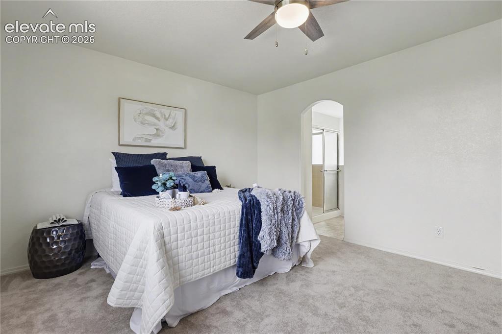 Image 17 of 41: Carpeted room featuring a ceiling fan, arched doorway, and an en-suite bath