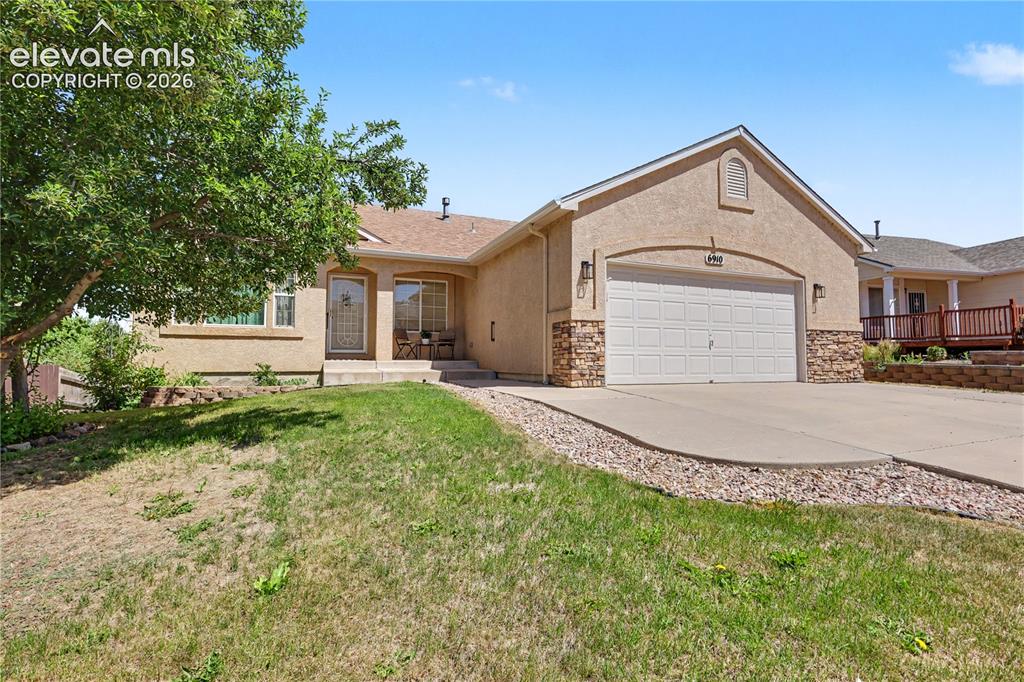 Image 2 of 41: Front exterior featuring stucco siding, stone accents, an attached garage,