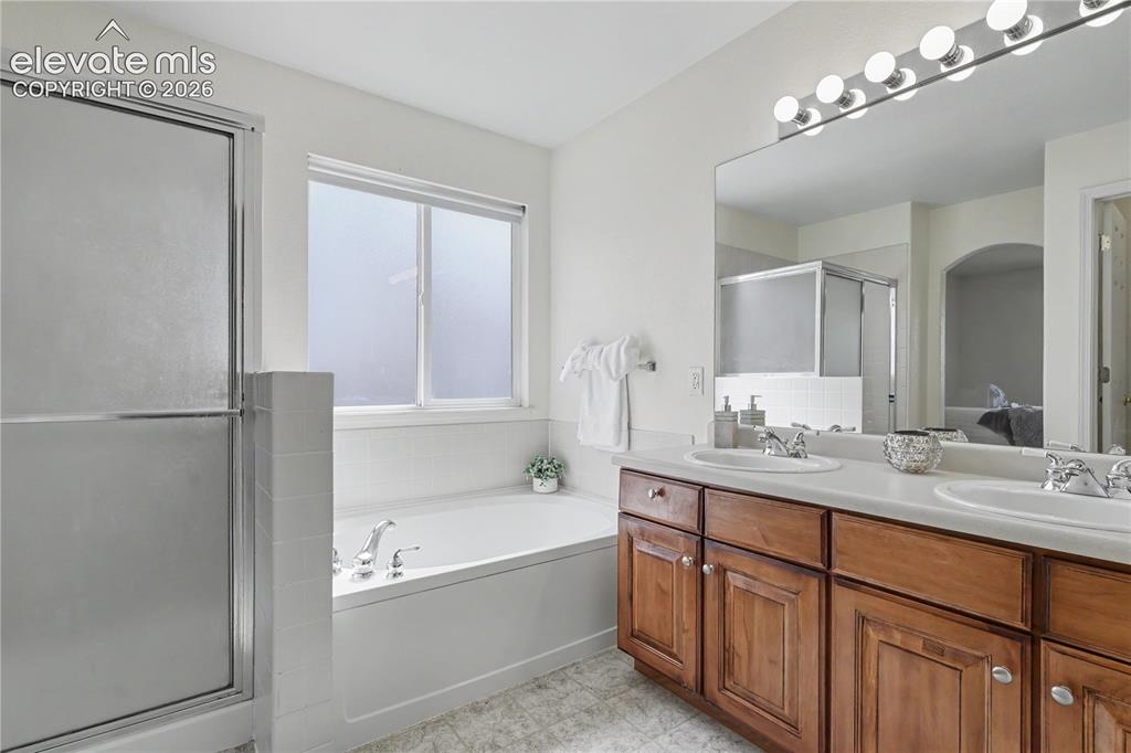 Image 21 of 41: Bathroom featuring a double vanity with wood cabinetry and dual sinks, a la