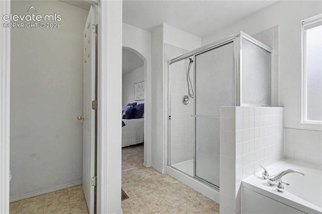 Image 22 of 41: Shower with sliding glass enclosure, white subway tile surround, and chrome