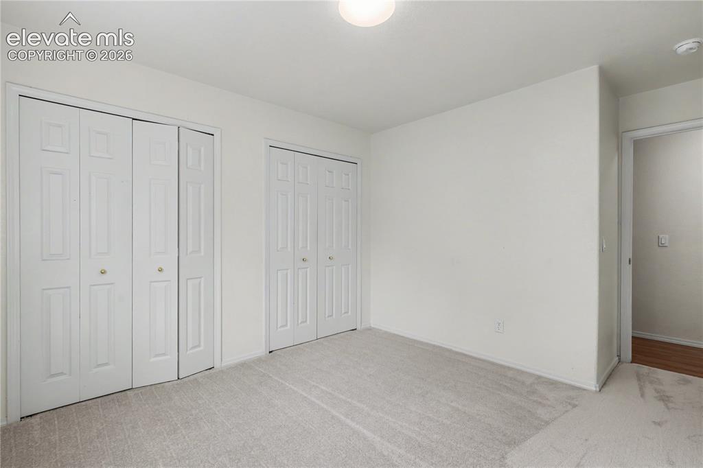 Image 25 of 41: Carpeted room featuring two sets of bi-fold closet doors with brass-toned h