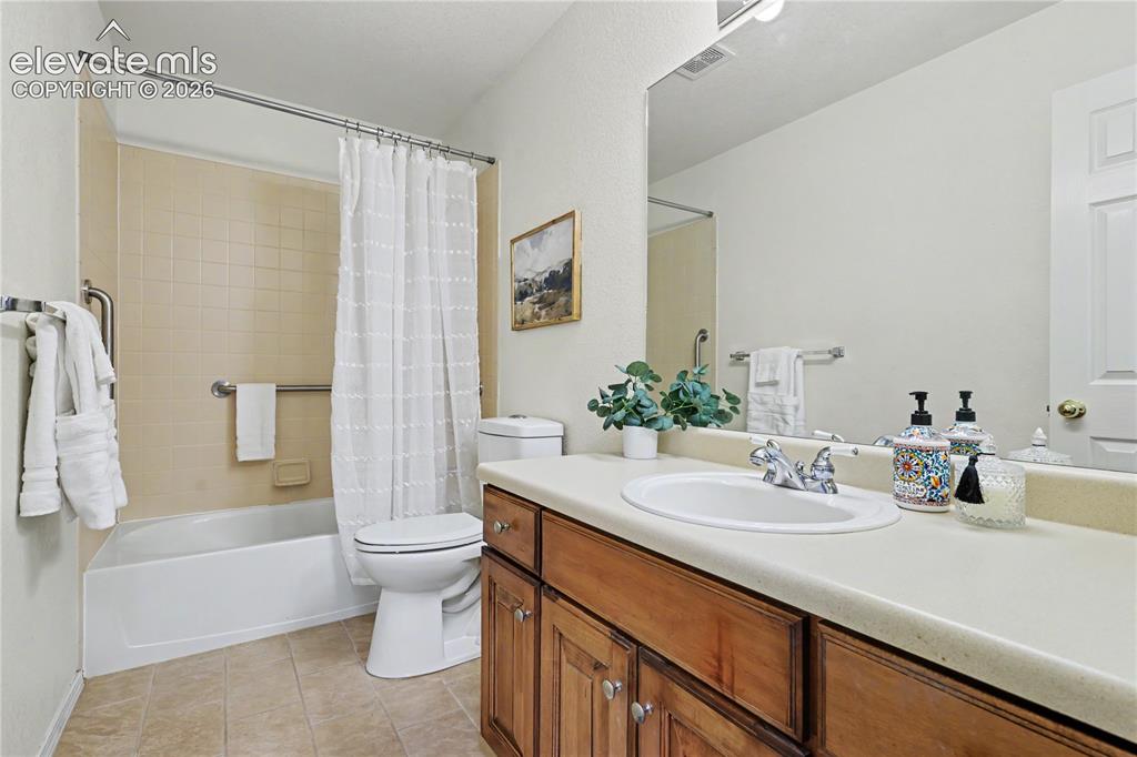 Image 26 of 41: Bathroom featuring a full vanity with wood-finish cabinetry, an integrated