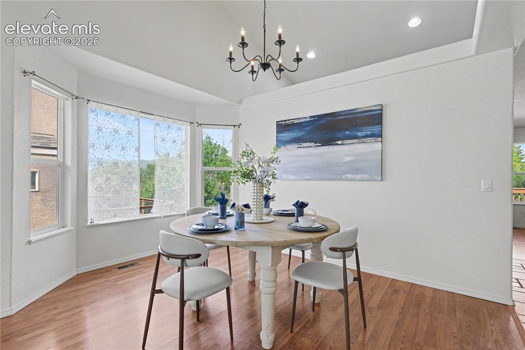 Image 6 of 41: Bay window dining area featuring wood-finish flooring, a contemporary chand