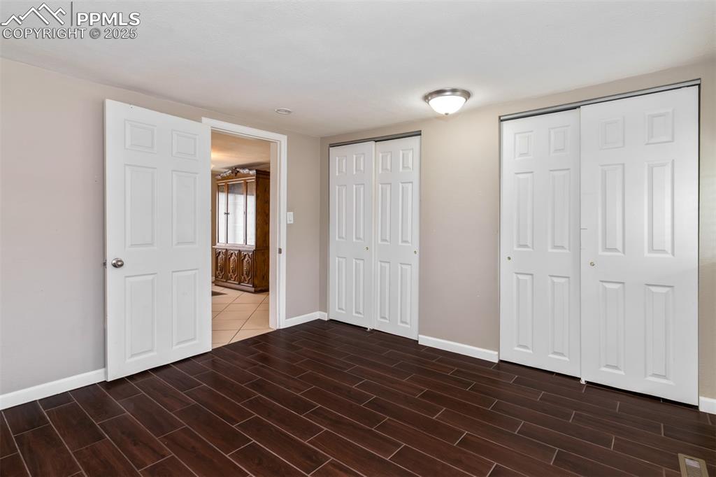 Image 11 of 22: Unfurnished bedroom with two closets and wood tiled floors