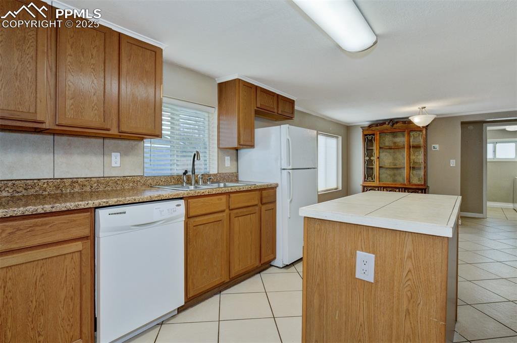 Image 4 of 22: Kitchen featuring a center island, light tile patterned floors, white appli