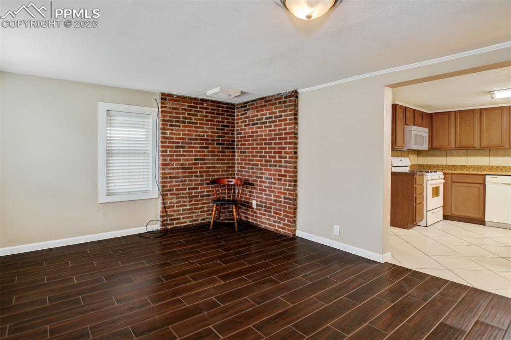 Image 6 of 22: Unfurnished living room featuring dark wood-type flooring, ornamental moldi