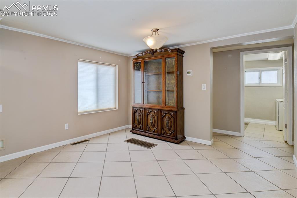 Image 9 of 22: Unfurnished dining area with crown molding and light tile patterned floors