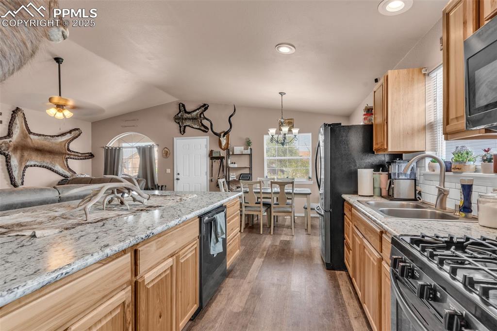 Image 12 of 37: Kitchen featuring lofted ceiling, dark wood-style floors, black appliances,