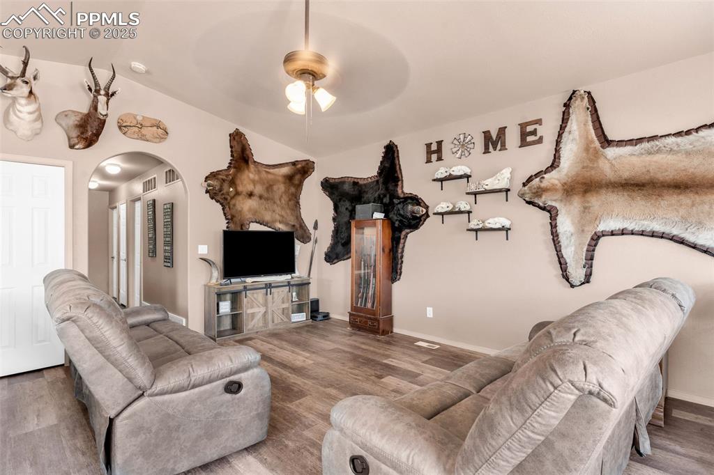 Image 7 of 37: Living room featuring wood finished floors, ceiling fan, and arched walkway