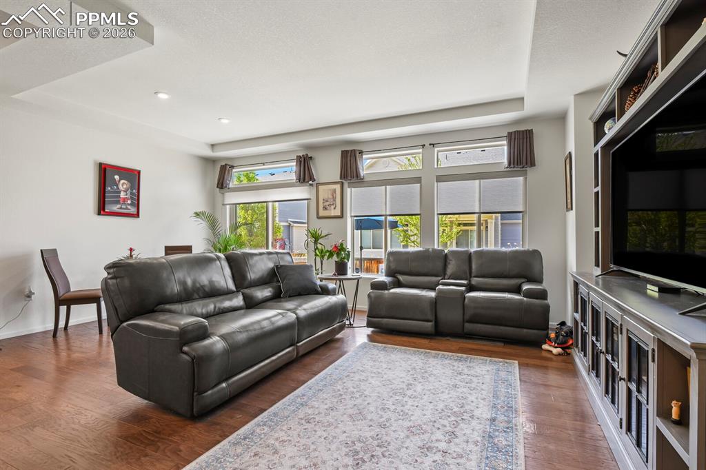 Image 14 of 39: Spacious living area featuring wood-finish flooring and a tray ceiling with