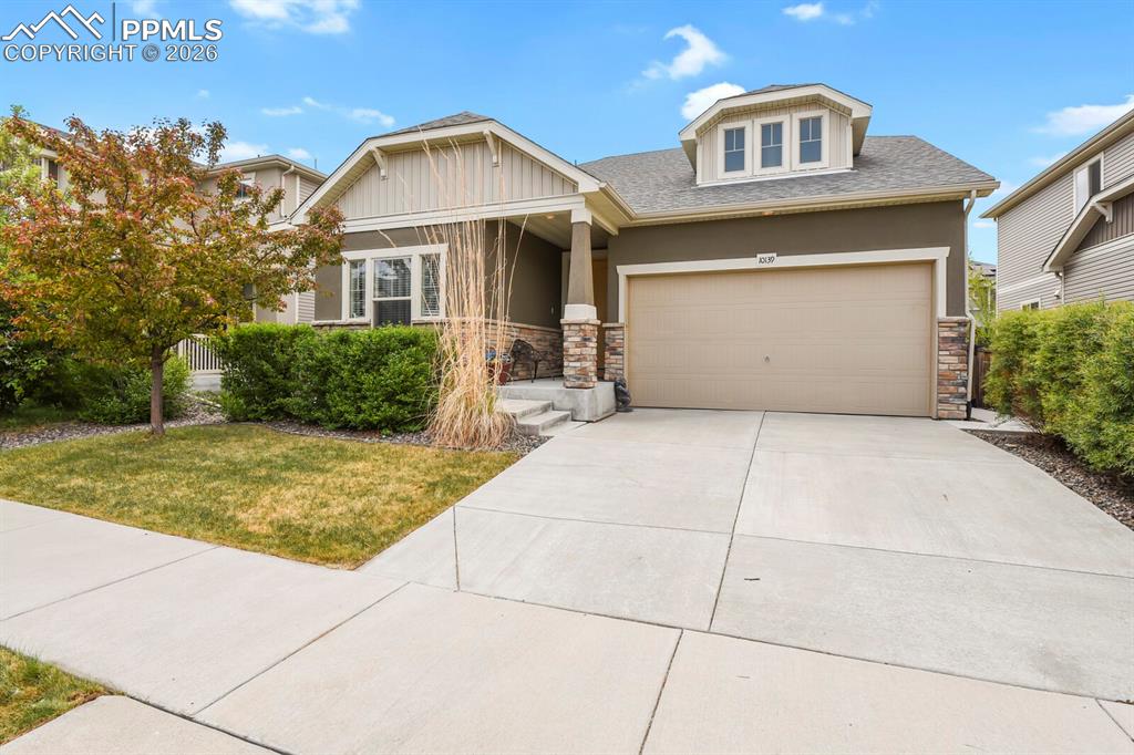 Image 2 of 39: Front exterior featuring a two-car garage, stone accents, stucco siding, a