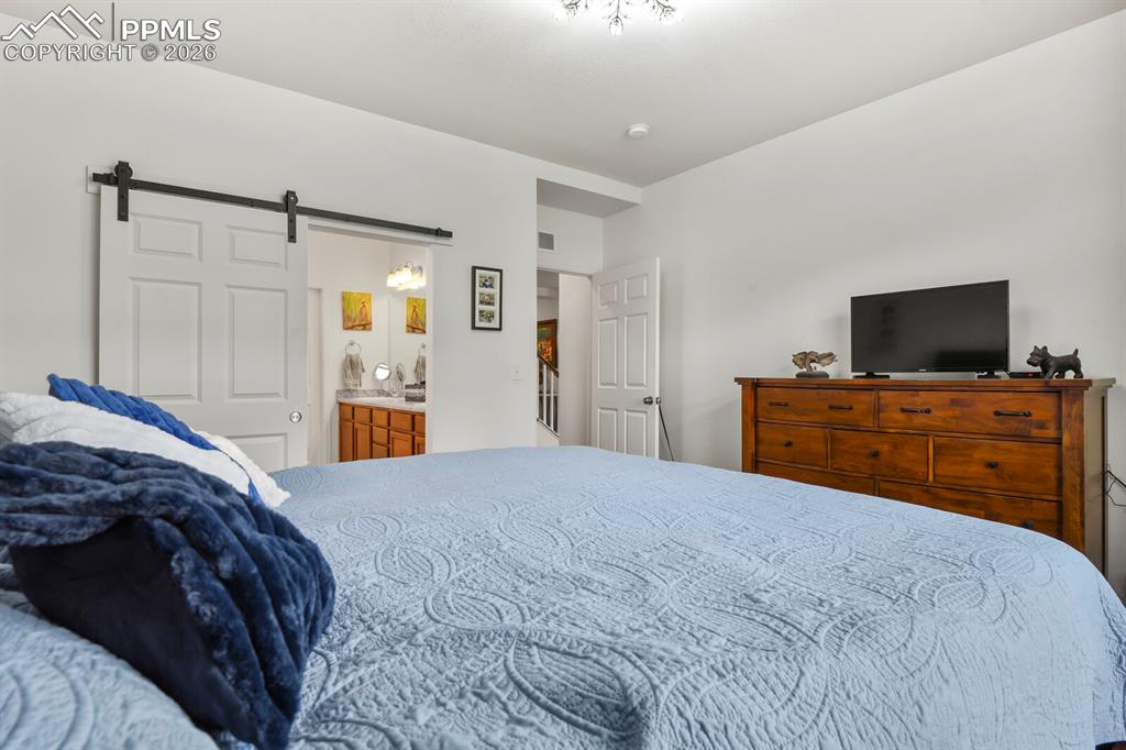 Image 20 of 39: Nice primary bedroom on the main level with a barn door leading the private