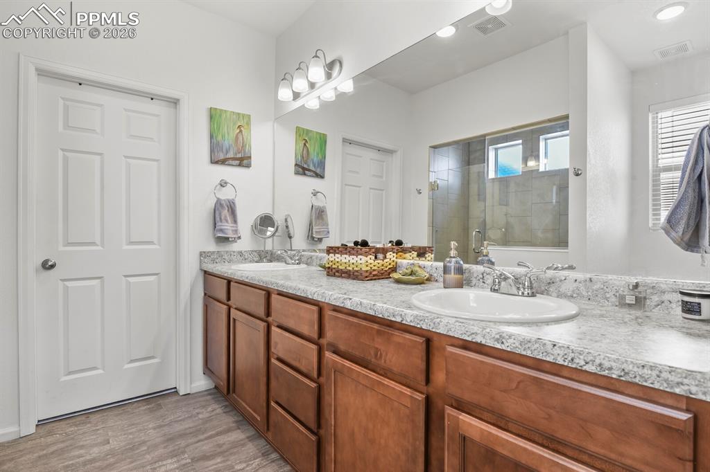 Image 21 of 39: Private primary bathroom featuring a double vanity, shower and access to th