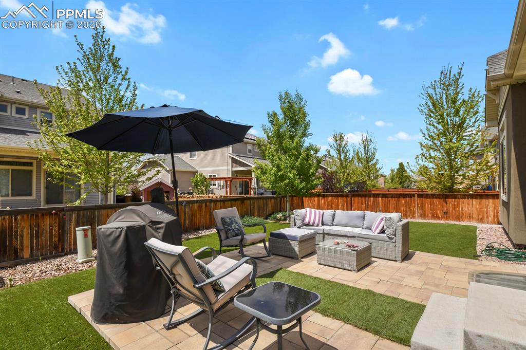 Image 34 of 39: Backyard featuring a paver patio and artificial turf offering low maintenan