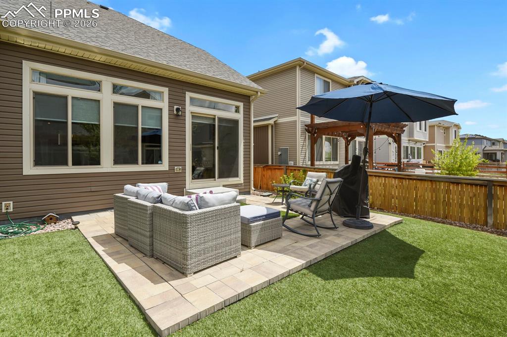 Image 35 of 39: Backyard featuring a paver patio and artificial turf offering low maintenan